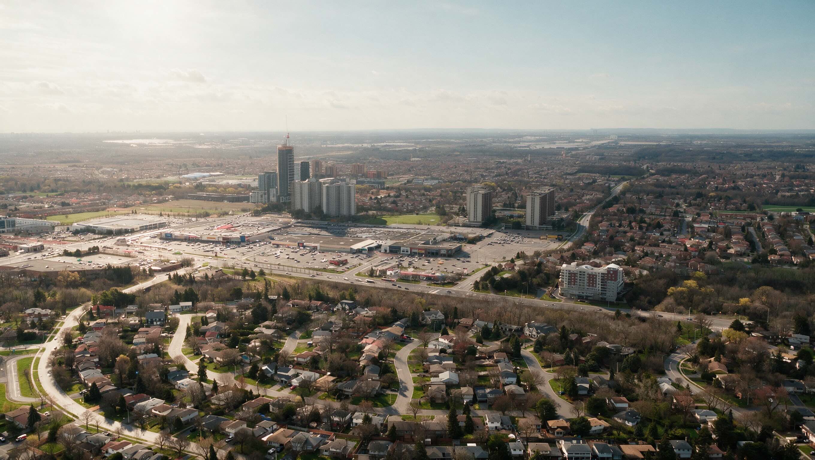 Aerial view over a city, residential streets in the foreground and towers on the horizon